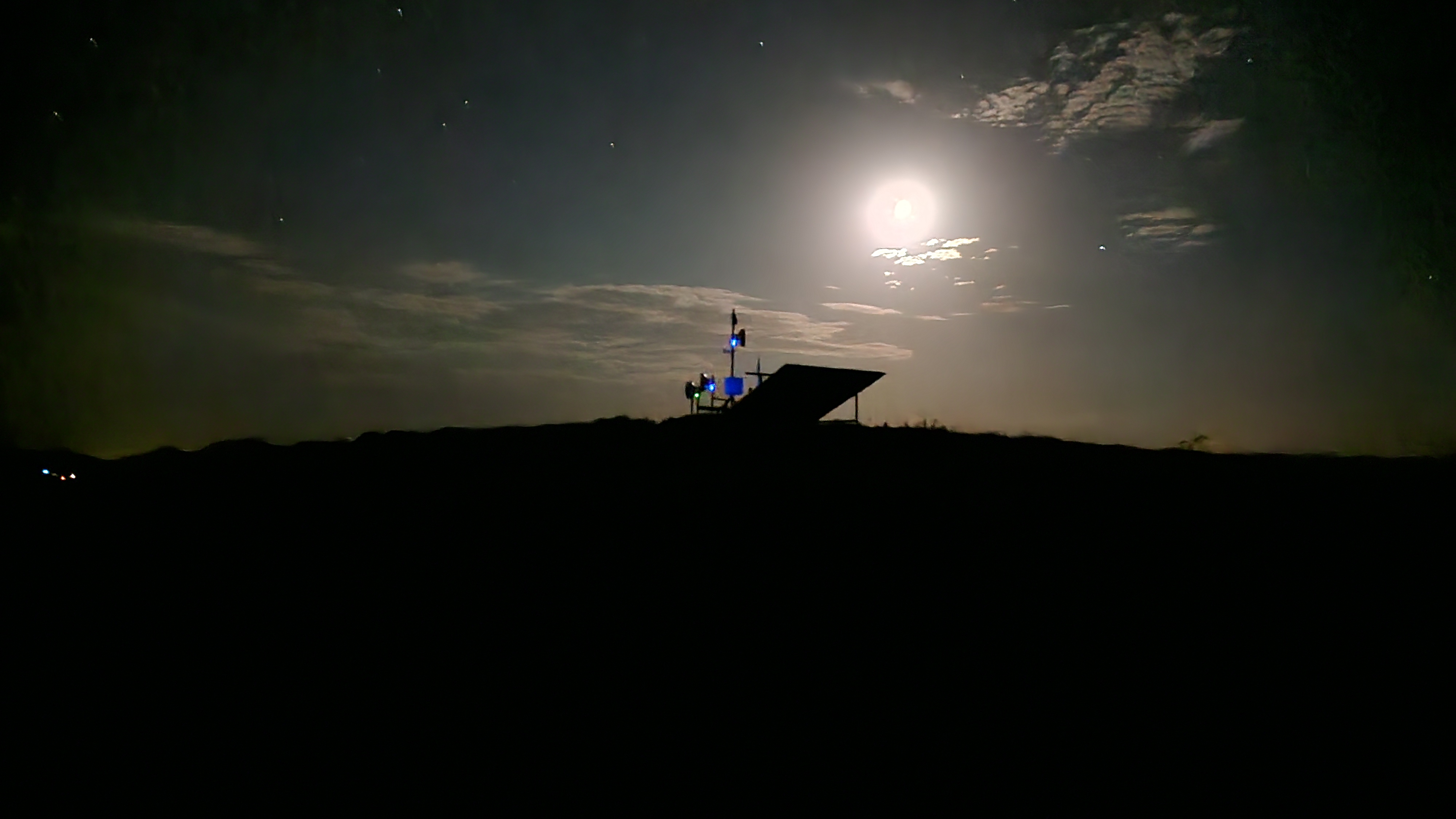 Tower equipment silhouetted against a full moon